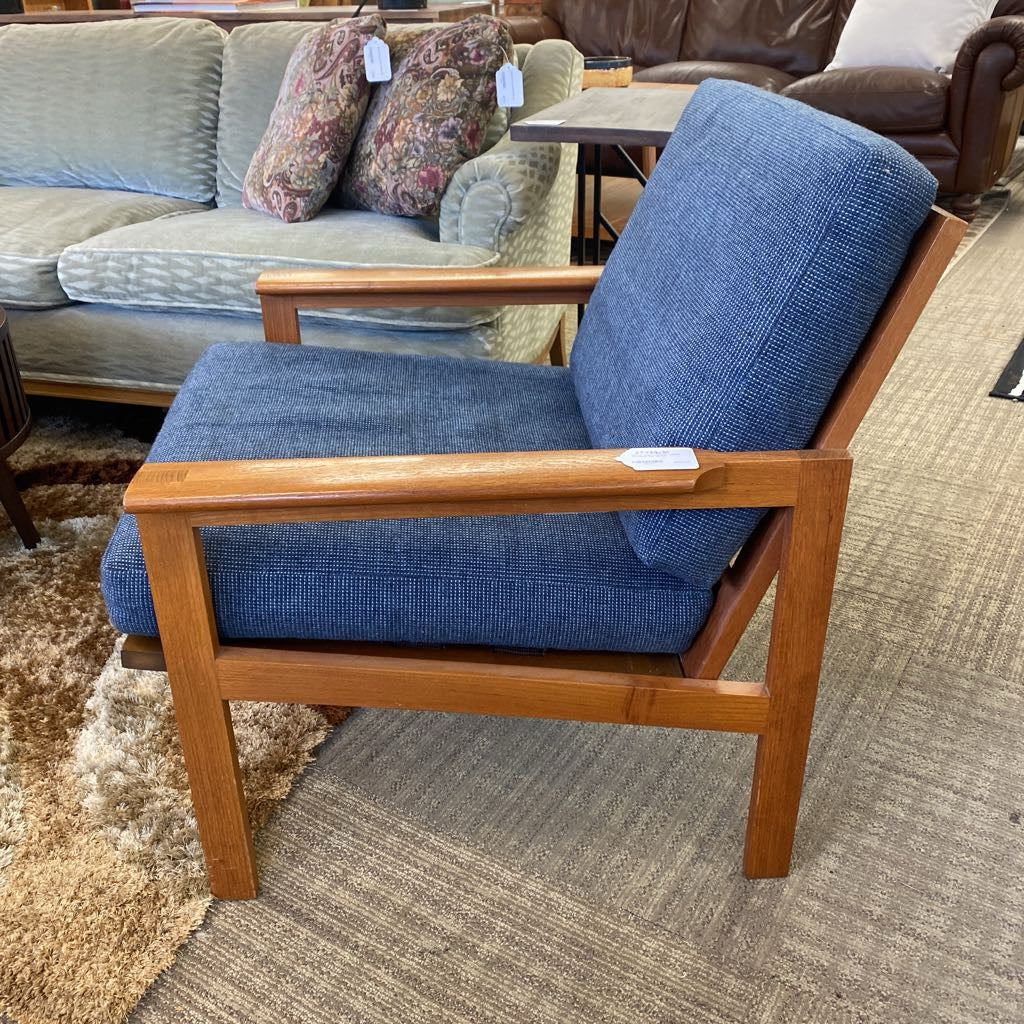 Blue armchair with wooden frame in a furniture store setting