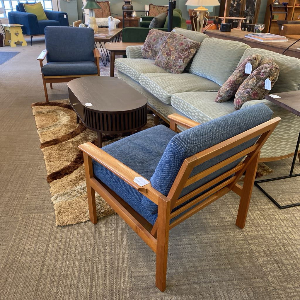 Sofa and chair set with wooden frame and blue cushions in a showroom setting.