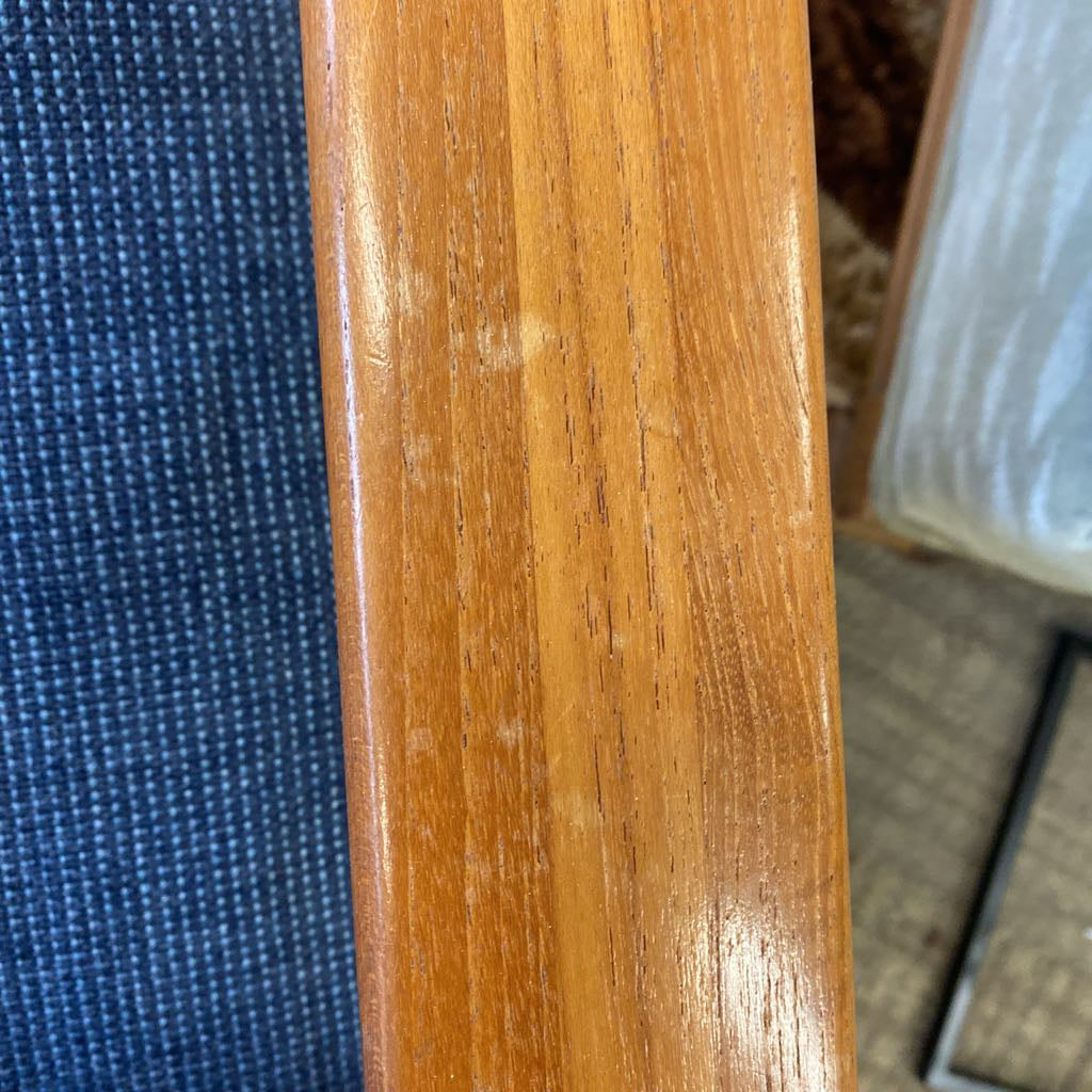 Close-up of a wooden chair leg with a blue fabric background
