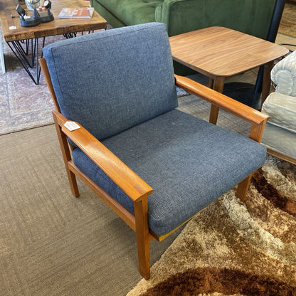 Blue cushioned chair with wooden armrests in a living room setting