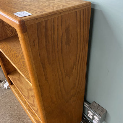 Wooden bookshelf against a wall with a power outlet below