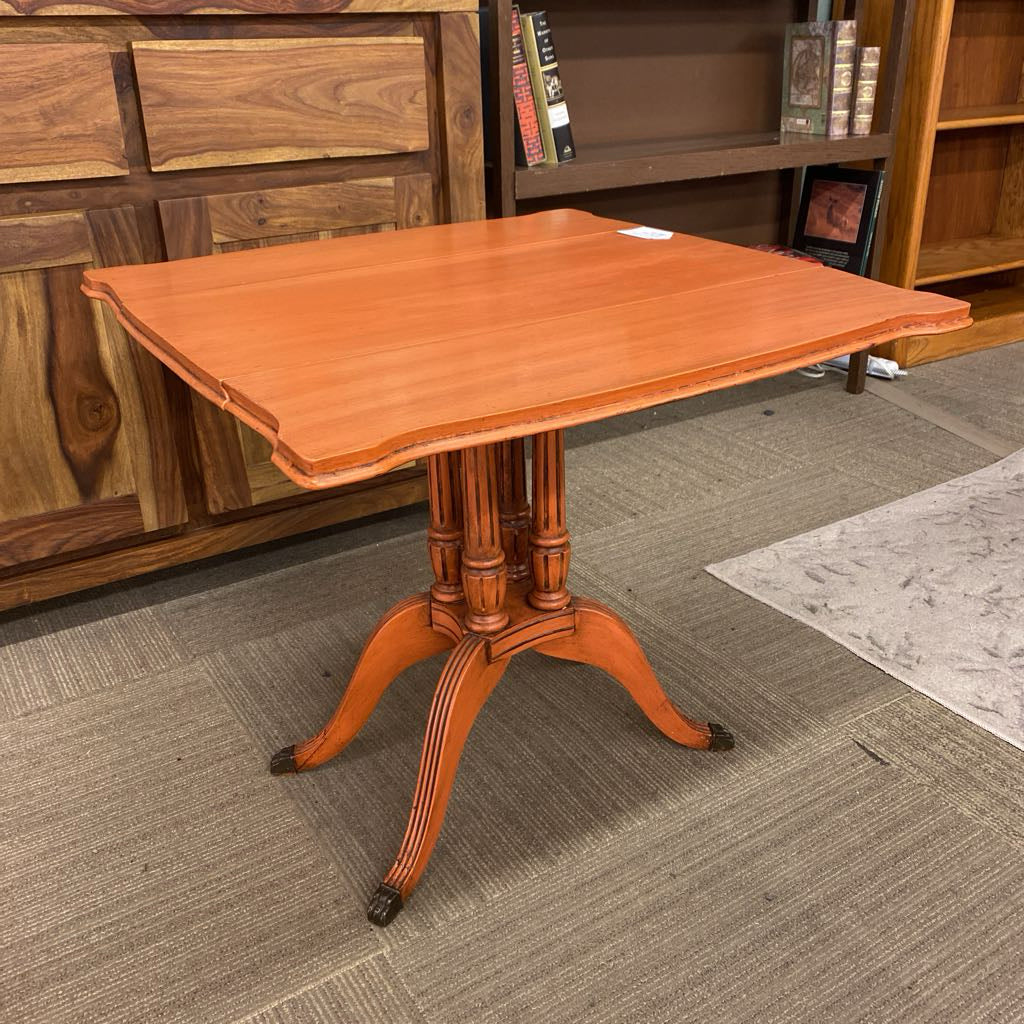 Wooden table with a pedestal base in a room with wooden bookshelves.