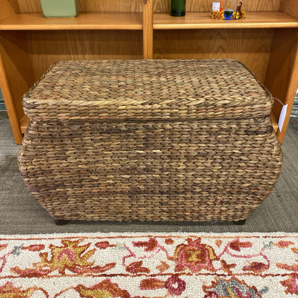 Woven storage basket on a carpeted floor with a wooden shelf in the background