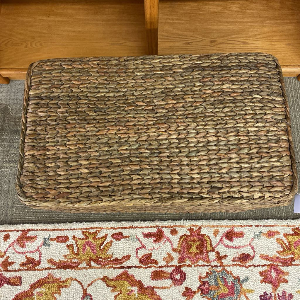 Woven mat on a wooden floor with a colorful rug underneath