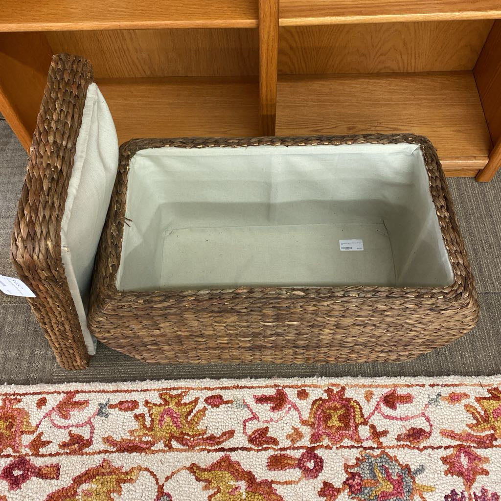 Wicker storage basket with a white interior on a carpeted floor.