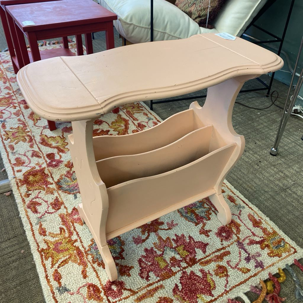 Beige magazine rack on a patterned rug with a blurred background