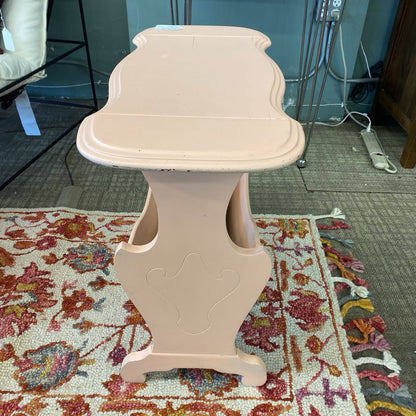 Beige decorative pedestal table on a patterned rug with a room background