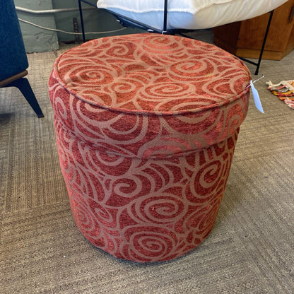 Red patterned ottoman on a carpeted floor