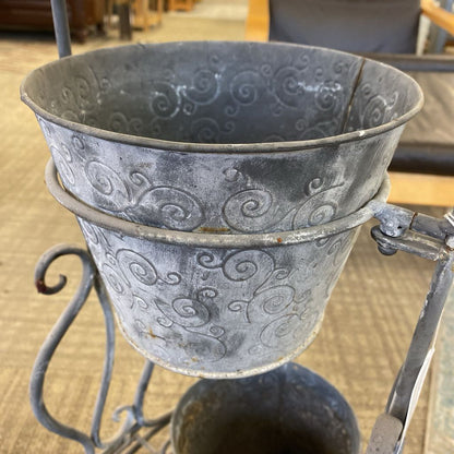 Decorative metal bucket with intricate designs on a stand.