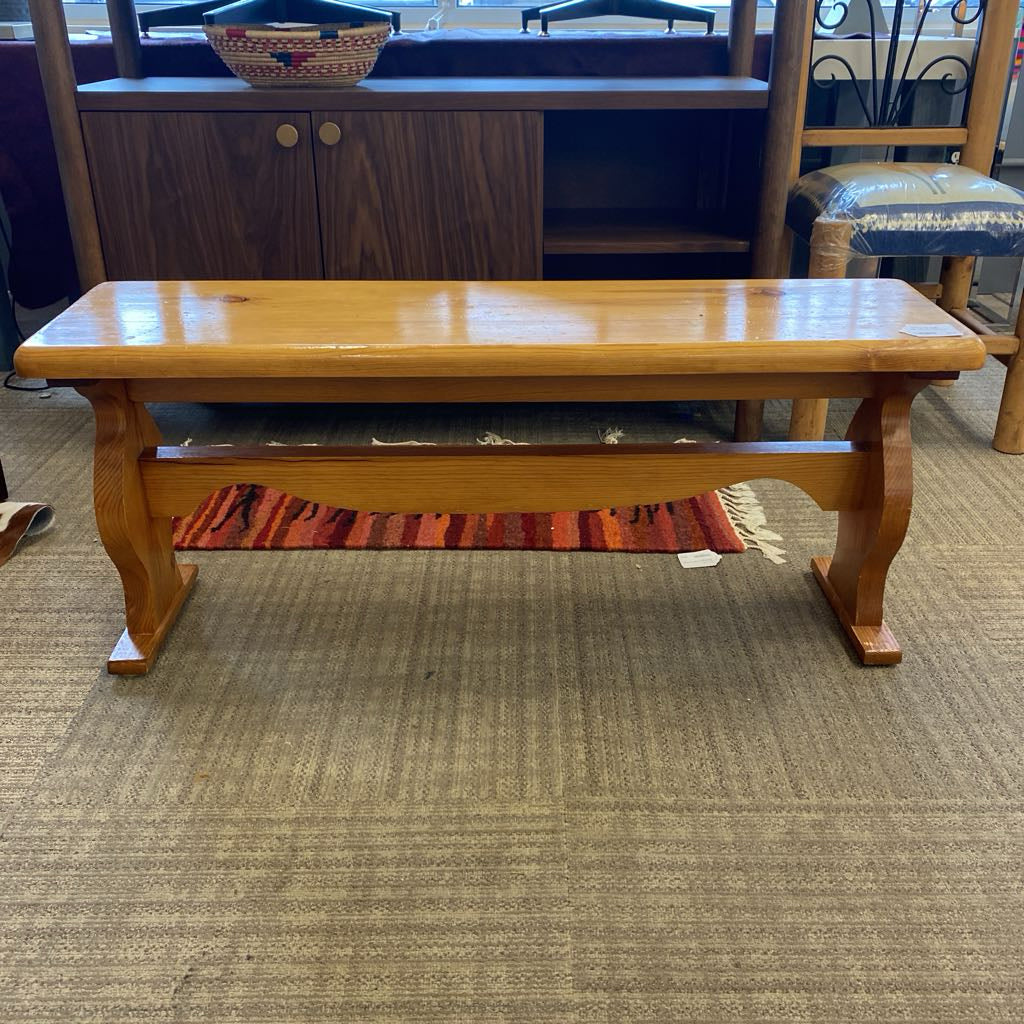 Wooden bench on a carpeted floor with a cabinet in the background