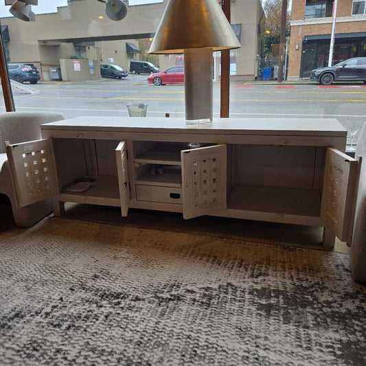 Wooden entertainment console with open doors on a patterned rug, street view outside.