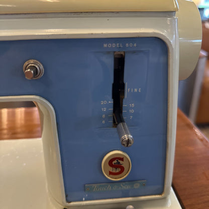 Vintage sewing machine with blue panel and brand logo on a wooden surface