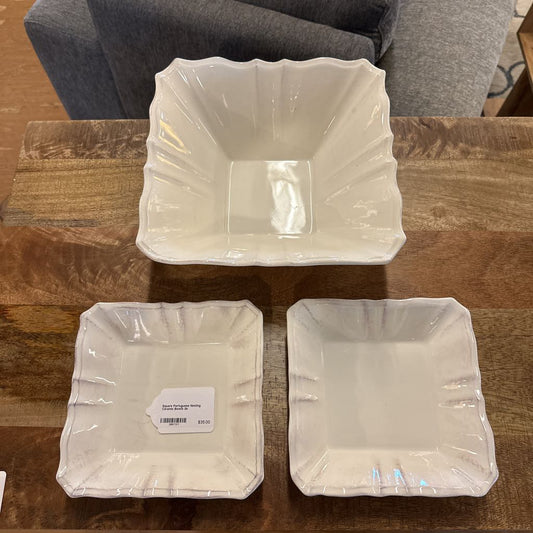 Three square plastic containers on a wooden surface with a gray couch in the background.