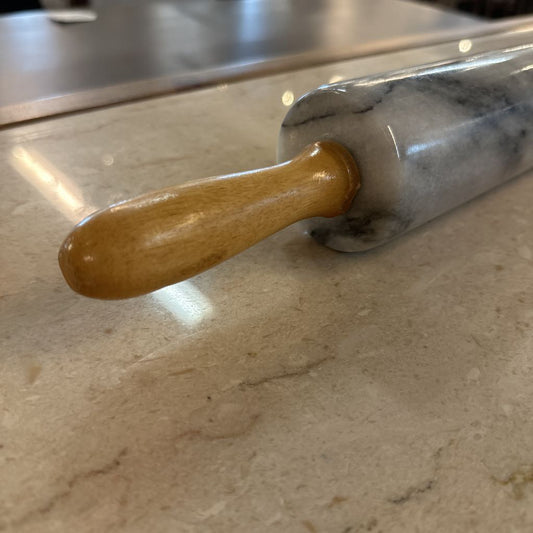 Rolling pin with a wooden handle on a marble surface