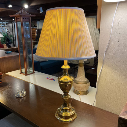 Decorative lamp with a yellow pleated shade on a wooden surface.