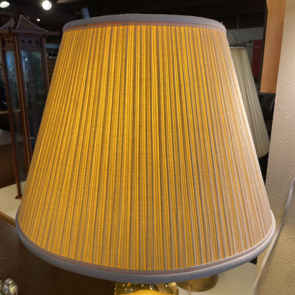 Yellow pleated lampshade on a lamp base with a blurred indoor background