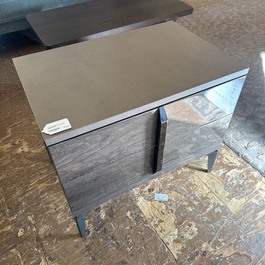Wooden side table with a flat top and two drawers on a textured floor.