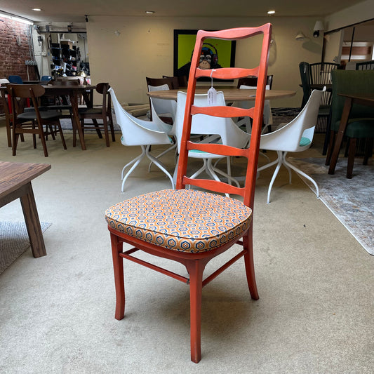 Red chair with patterned cushion in a room with tables and chairs