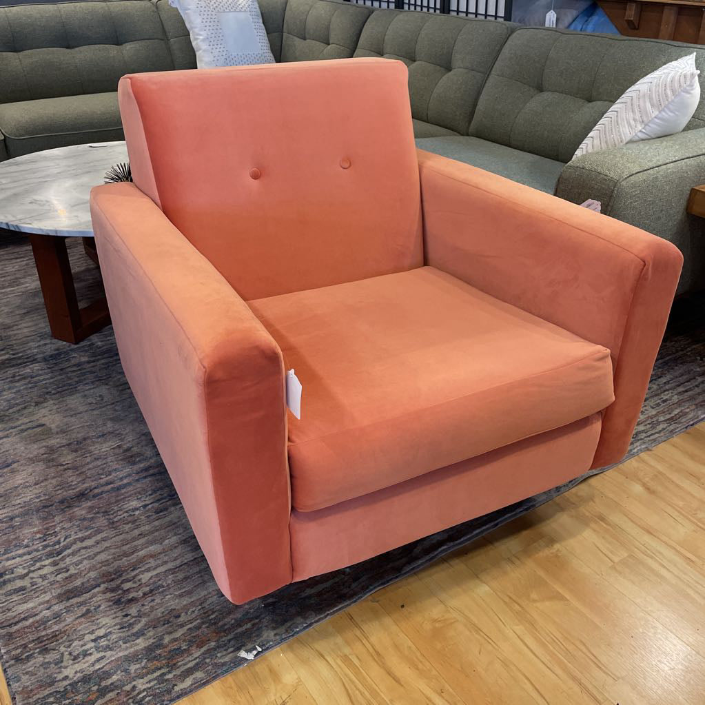 Orange armchair in a room with a gray sofa and wooden floor.