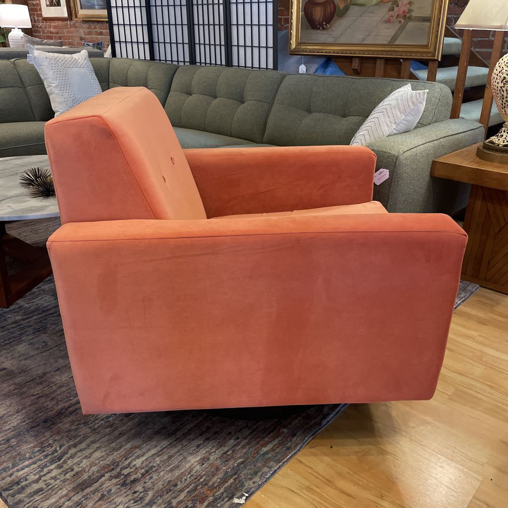 Orange armchair in a room with a green sofa and various decor items.