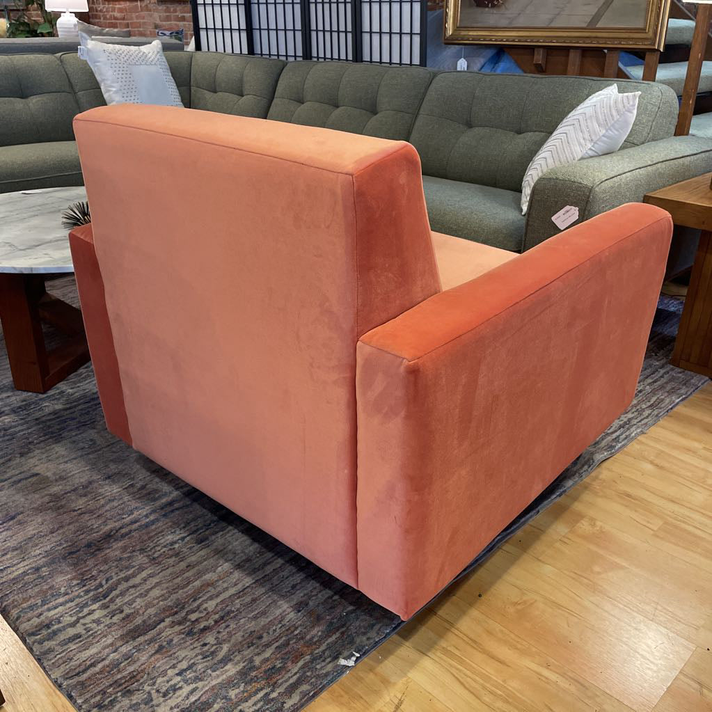 Orange armchair in a room with a green sofa and wooden floor.