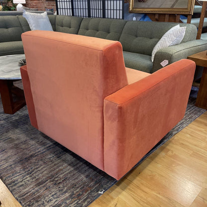 Orange armchair in a room with a green sofa and wooden floor.
