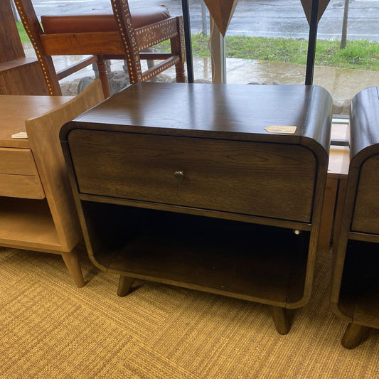 Wooden nightstand with a drawer in a room with furniture and a rainy outdoor view.