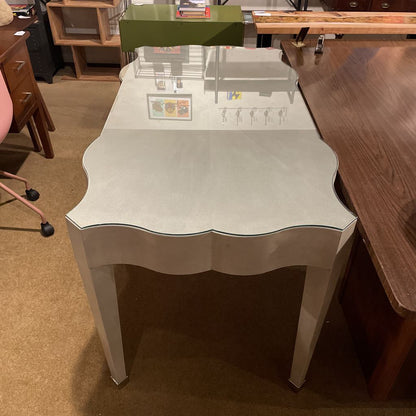 White table with a scalloped edge in a room with wooden furniture and a carpeted floor.