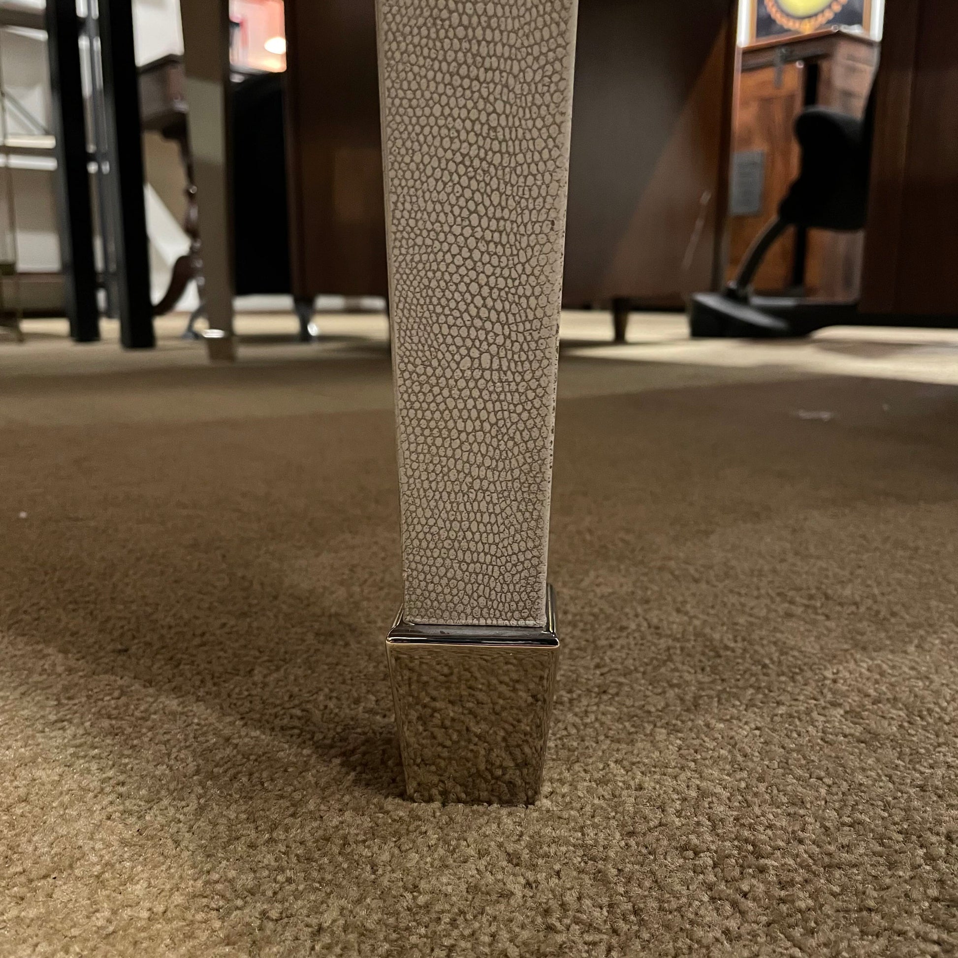 Textured metal leg on a carpeted floor with blurred background