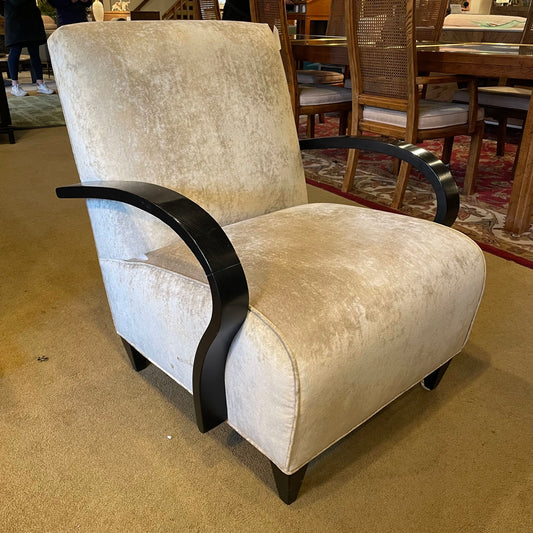 Beige armchair with black armrests in a room with a dining table and chairs.