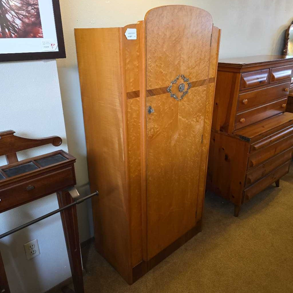 Wooden wardrobe with decorative emblem in a room with furniture and decor.