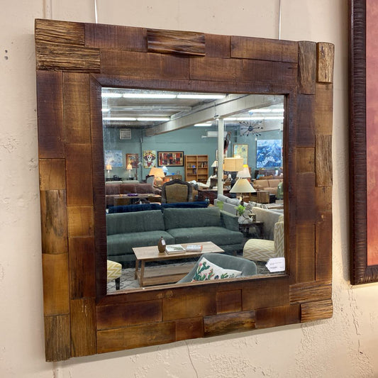 Wooden framed mirror reflecting a room with furniture