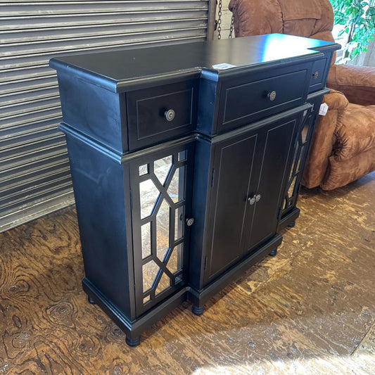 Black wooden sideboard with drawers and cabinet doors on a wooden floor.