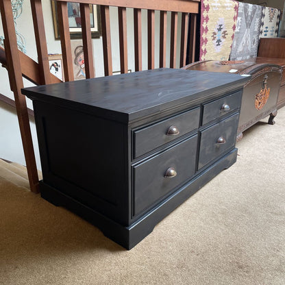 Dark wooden dresser with multiple drawers in a room with a staircase and patterned rug.