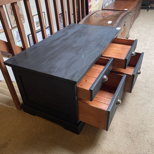 Wooden drawer unit with black top and open drawers on a carpeted floor.