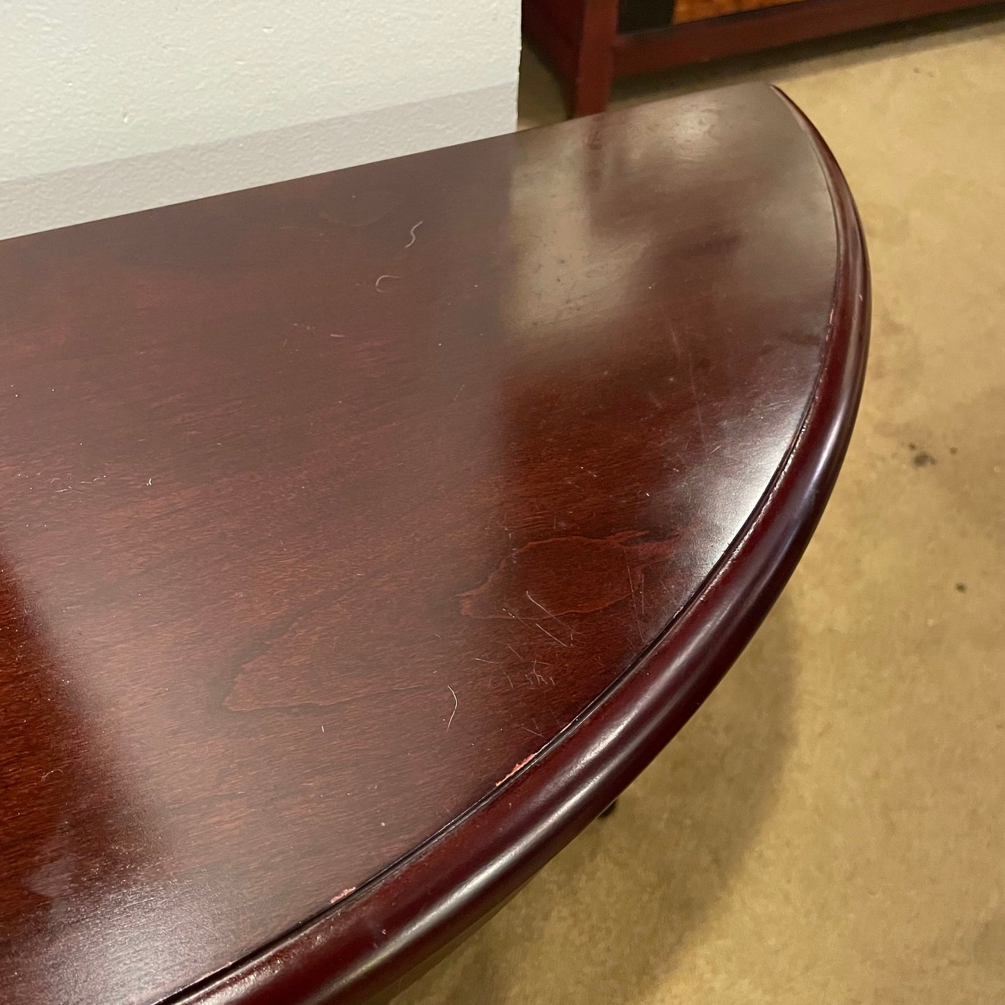 Close-up of a dark wooden table corner with visible scratches.