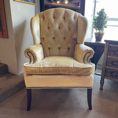 Beige armchair in a room with a plant and furniture.