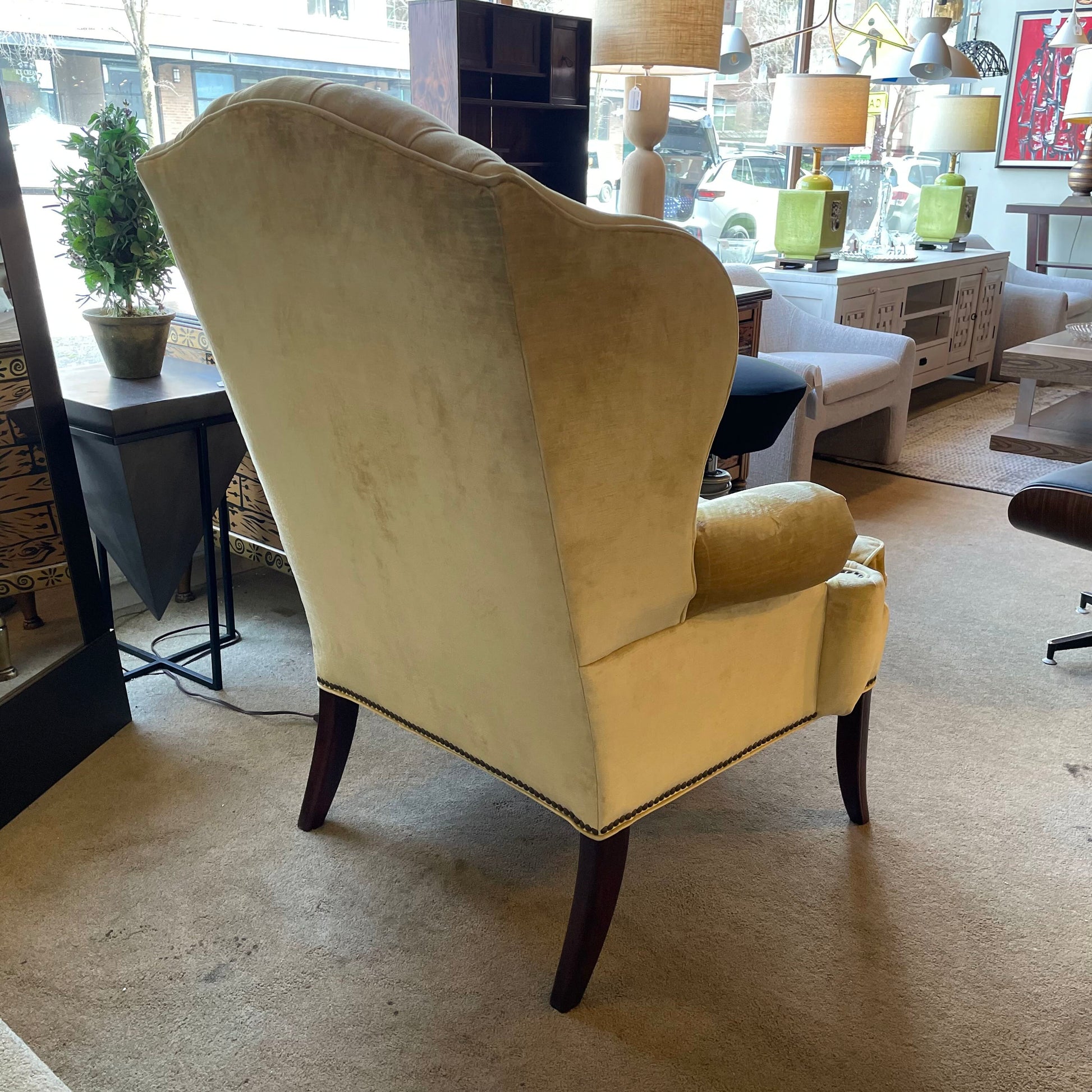 Beige wingback chair in a room with furniture and decor