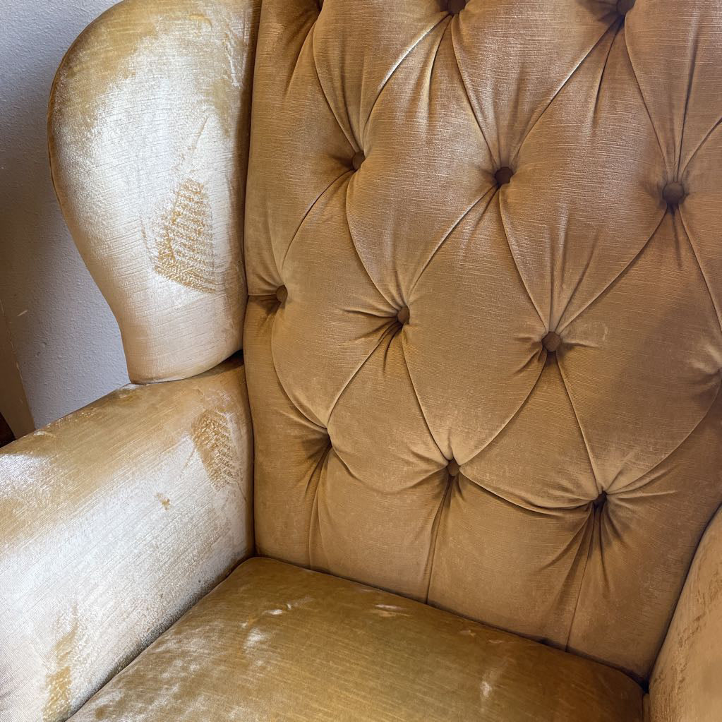 Beige armchair with tufted backrest showing signs of wear.