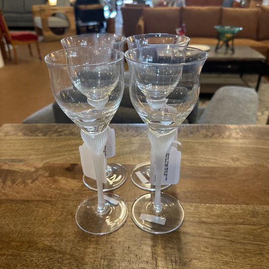 Three clear wine glasses on a wooden table with a blurred indoor background