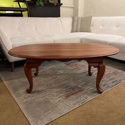 Wooden coffee table in a living room setting with a sofa and rug.