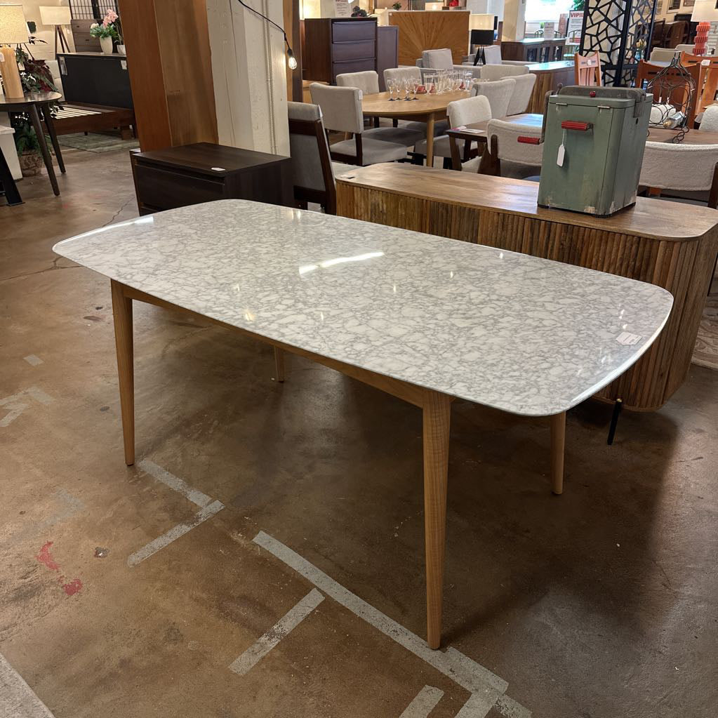 Dining table with marble-like top and wooden legs in a showroom setting