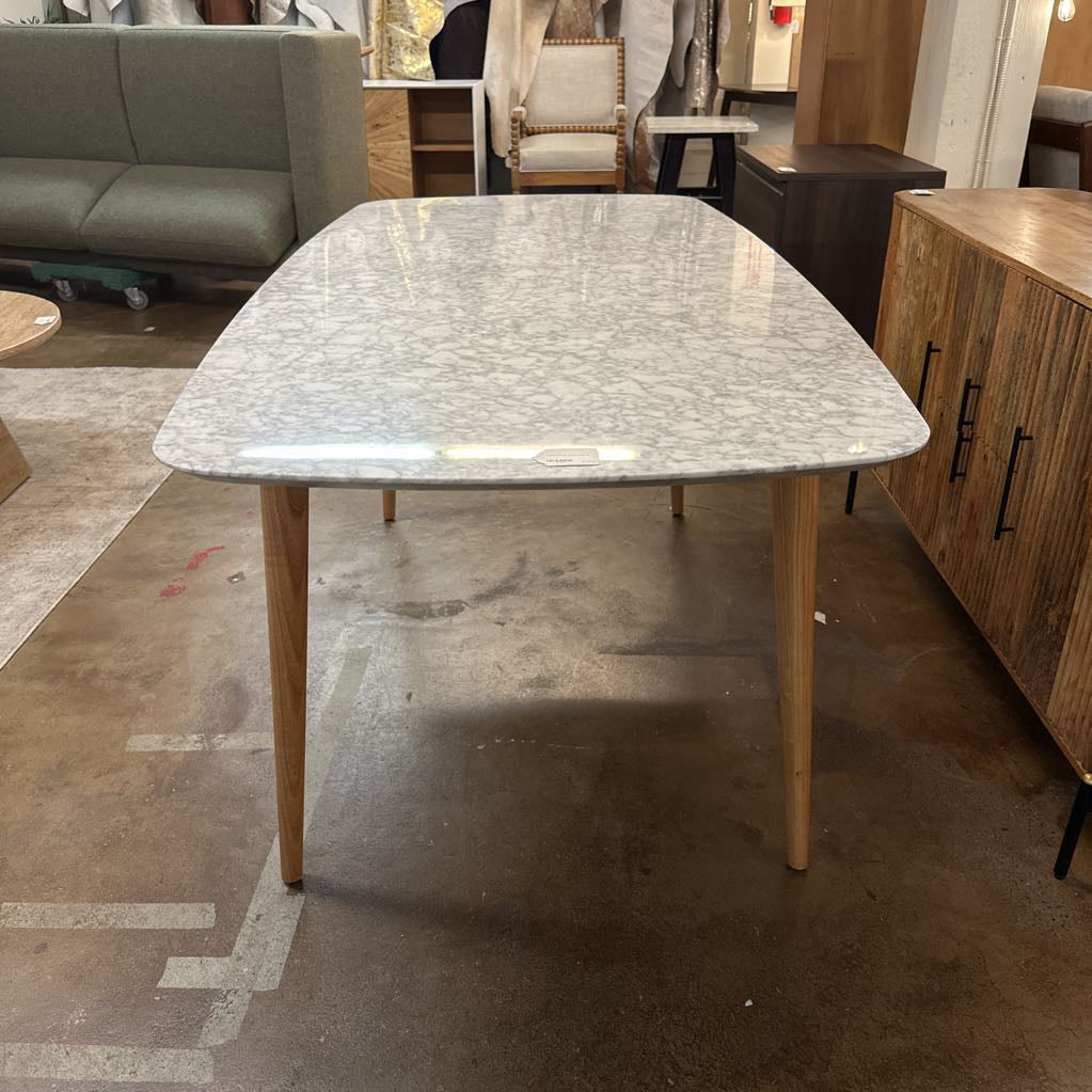 Dining table with marble-like top and wooden legs in a showroom setting