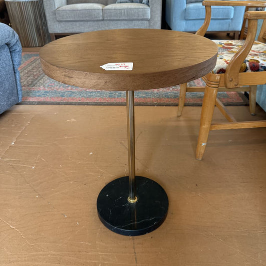 Wooden side table with black marble base in a room setting