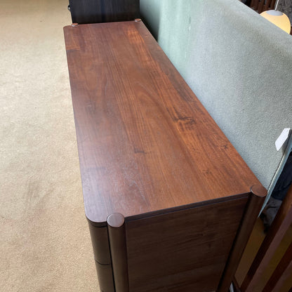 Wooden bench against a gray couch on a beige carpet