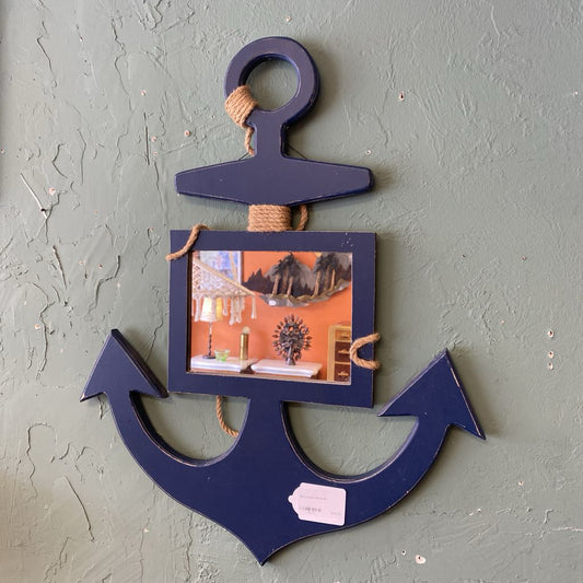 Navy blue anchor-shaped picture frame with a small photo inside, on a gray wall.