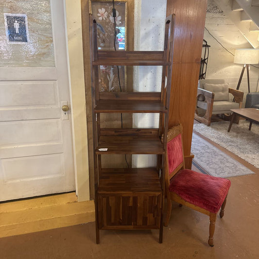 Wooden bookshelf with a red cushioned chair in a room setting.