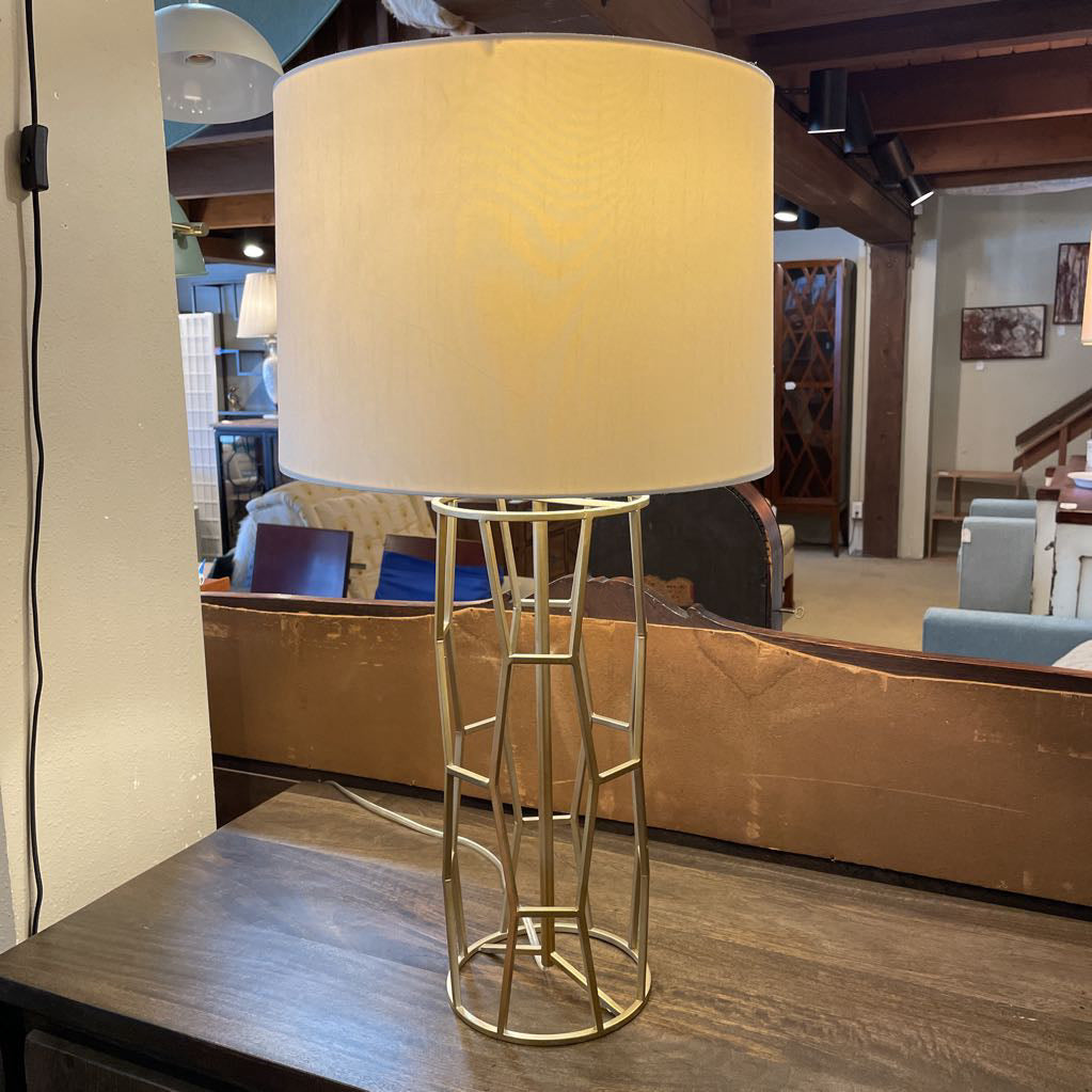 Table lamp with beige shade on a wooden table in a room setting