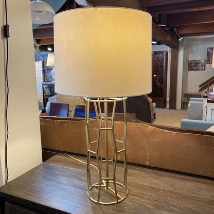 Table lamp with beige shade on a wooden table in a room setting