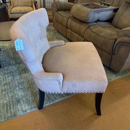 Beige armchair with a price tag in a room with a brown sofa and green rug.